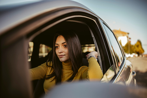 Young woman driving a car in the city. Young woman driving a car in the city. Portrait of a beautiful woman in a car, looking out of the window. Travel and vacations concepts