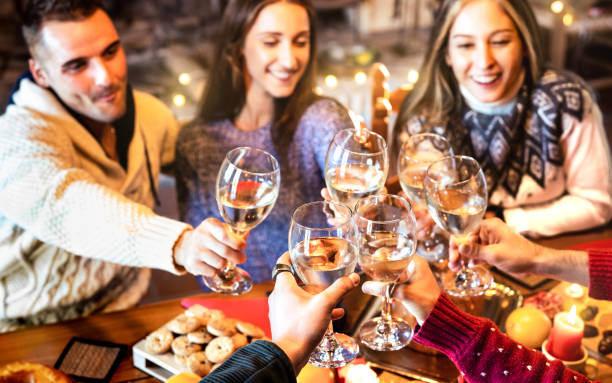 ホームディナーパーティーでシャンパンワインを乾杯クリスマスを祝う人々グループ - 時間を楽しんで一緒に楽しむ若い友人と冬の休日のコンセプト - 焦点を当てた低いガラスと暖かいフィ� - champagne toast wine restaurant ストックフォトと画像