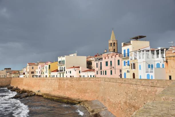 skyline de la histórica ciudad de alghero iluminado por el sol en un día tormentoso, cerdeña / italia - alghero fotografías e imágenes de stock