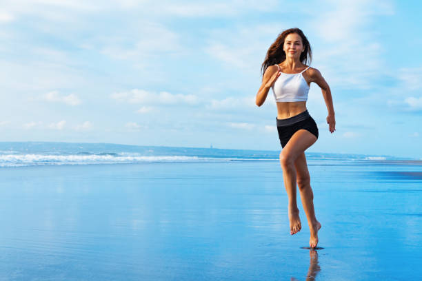 ragazza sportiva che corre in spiaggia lungo il surf sul mare - weight scale dieting weight loss foto e immagini stock