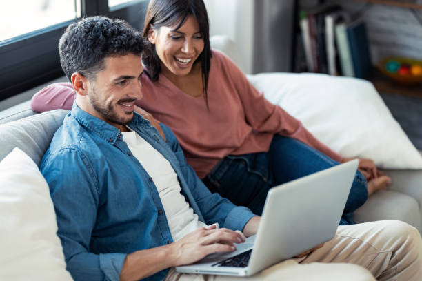 istock Happy beautiful couple using computer while sitting on the couch at home. 1282650251