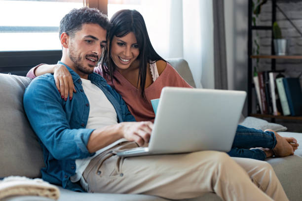 istock Happy beautiful couple using computer while sitting on the couch at home. 1282650899