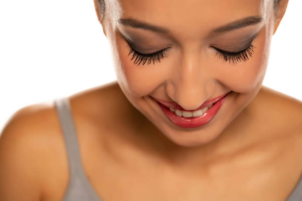 Cheerful young woman wearing blue nail polish, bright earrings, smiling while posing playfully during candid photoshoot