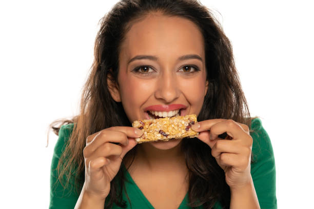 istock young dark skinned woman eating cereal bar 1282654037