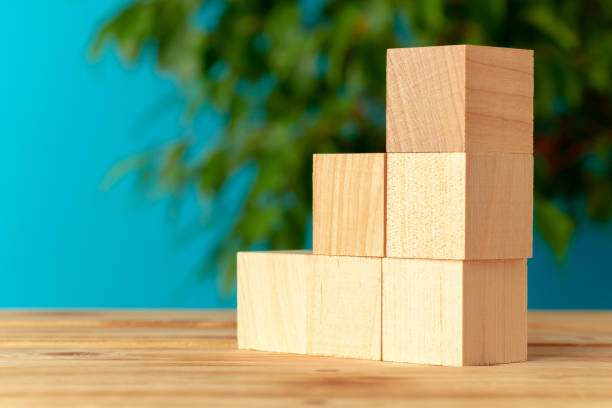 istock Wooden blocks on desk against blurred plant background 1282654415