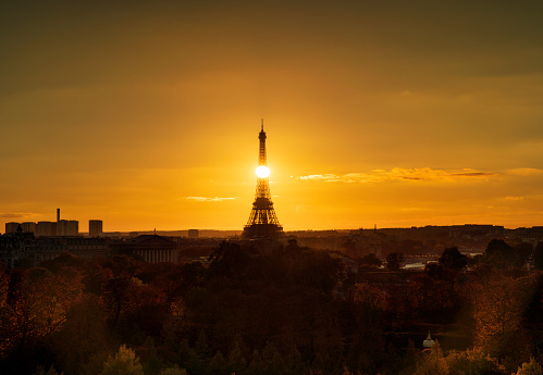 Sunset directly behind the Eiffel Tower city landscape in Paris, France.