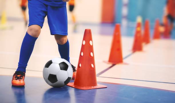 allenamento di calcio a 5 per bambini. allenamento di calcio dribbling esercitazione cono. giovane giocatore di calcio indoor con un pallone da calcio in un palazzetto dello sport. giocatore in uniforme blu. antefatti sportivi - futsal indoors soccer ball soccer foto e immagini stock