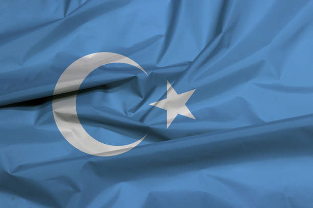 Fabric flag of East Turkestan. Crease of Uyghuristan flag background stock photo