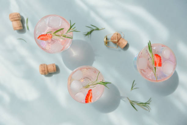 bevanda estiva con spumante bianco. cocktail di frutta rinfrescante fatto in casa o punch con champagne, fragole, cubetti di ghiaccio e rosmarino su sfondo azzurro. - champagne pink strawberry champaigne foto e immagini stock