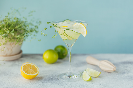 Glass of cucumber cocktail or mocktail, refreshing summer drink with crushed ice and sparkling water on wooden background.