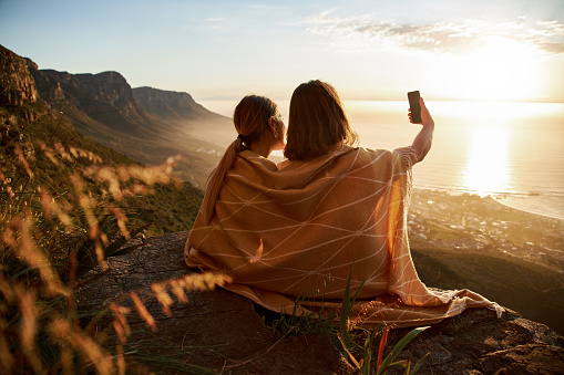 Rear view of young couple taking selfie on the mountain top.