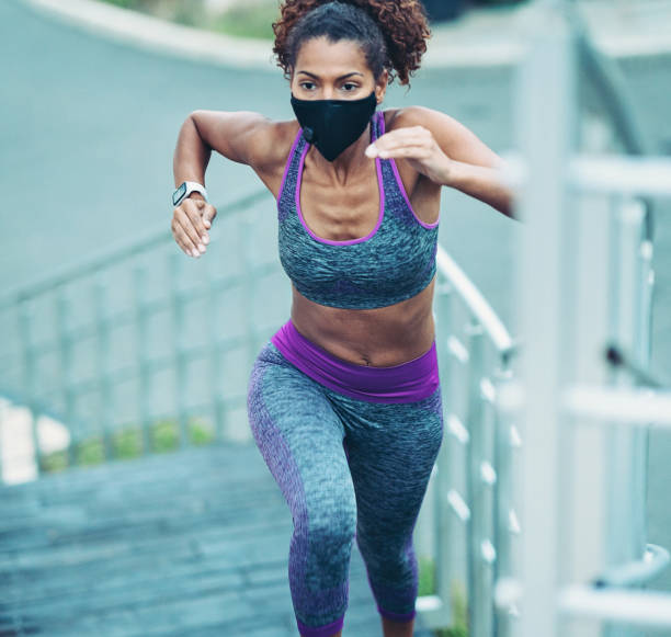 istock African ethnicity woman jogging outdoors wearing a face mask 1282663889