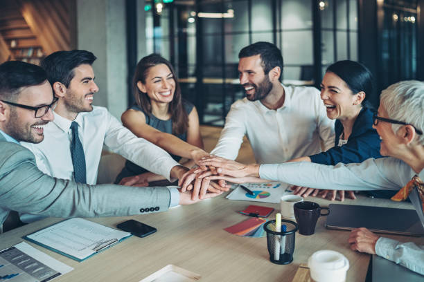 istock Group of smiling business persons stacking hands across the table 1282663906