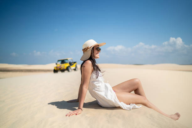 Side view of a young woman sitting in sand dunes in Jericoacoara Side view of a young woman sitting in sand dunes in Jericoacoara ceará state brazil stock pictures, royalty-free photos & images