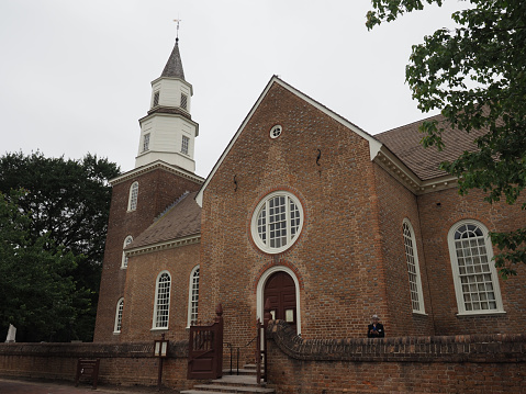 An old rustic white church sits in the countryside with a steeple and cross on top