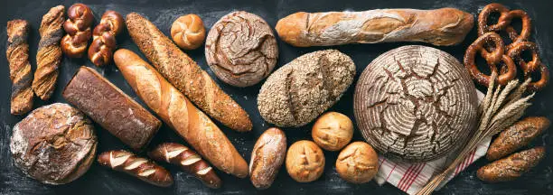 Photo of Delicious freshly baked bread assortment on dark rustic background