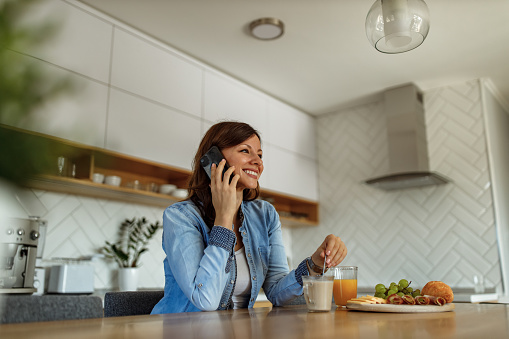 Happy brunette woman talking with her friends over the phone.