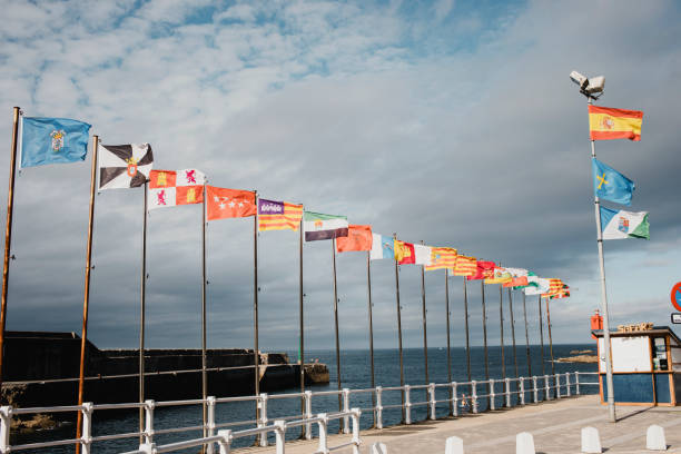 seascape of cudillero village fishing port, with all the region governments flags of spain, in a cloudy day, in the north of spain, in asturias. - spain flag built structure cloud imagens e fotografias de stock