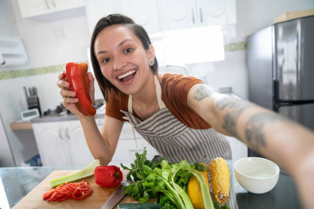 essen vlogger macht ein selfie beim kochen zu hause - vegan food fotos stock-fotos und bilder