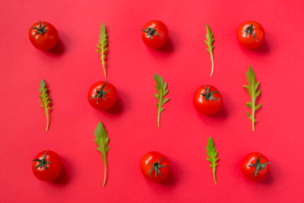 istock set of red fresh cherry tomatoes and arugula leaves on red background. 1282671697