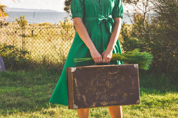 femme dans la robe verte retenant une valise dans ses mains. concept de voyage. espace photo.copy vintage. - suitcase retro revival women old fashioned photos et images de collection