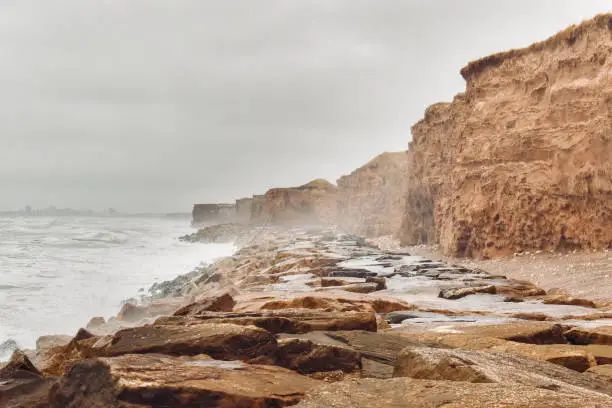 Photo of cliff on the Argentine coast sunset clouded with waves