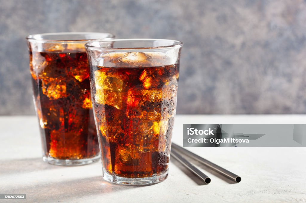 glass of cold cola soft drink with ice on wooden background Soda Stock Photo