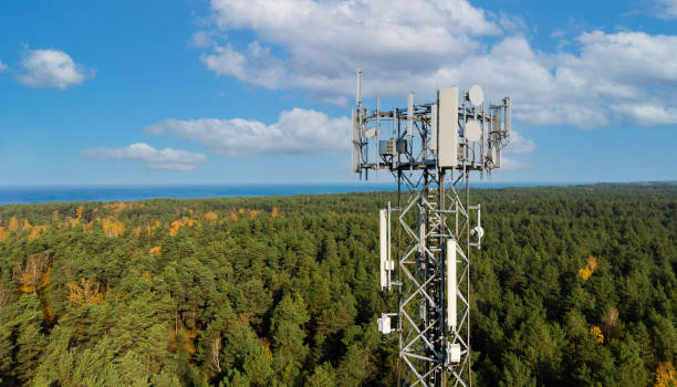 torre di telecomunicazione con antenne per la rete 5g su foresta e sfondo cielo blu. trasmissione internet mobile - tower foto e immagini stock