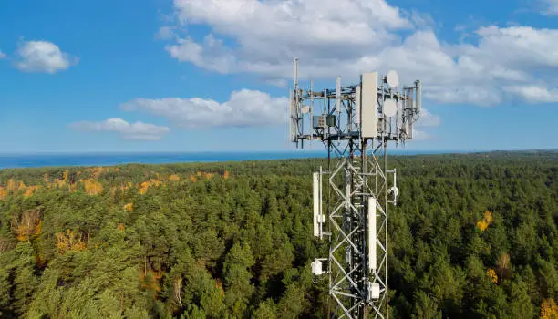 Photo of telecommunication tower with antennas for 5g network on forest and blue sky background. mobile internet broadcast