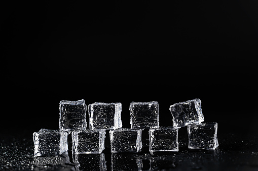 Ice cubes on black background covered with water drops, copy space provided. The scene is situated in controlled studio environment on black background. Photo is taken with Sony A7III camera