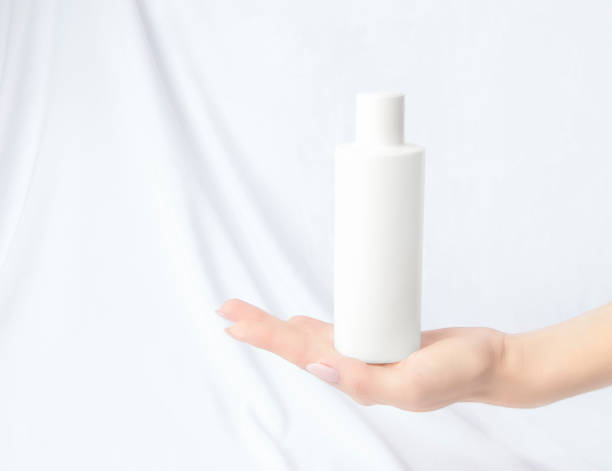 istock Mockup cosmetics. White bottle in a woman's hand. White background. Copy space. Minimalism 1282680003