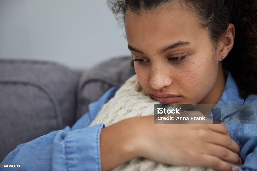 Sad and unhappy teenager looking out of the window Side view of sad and unhappy teenager sitting in sofa looking out of the window Teenager Stock Photo