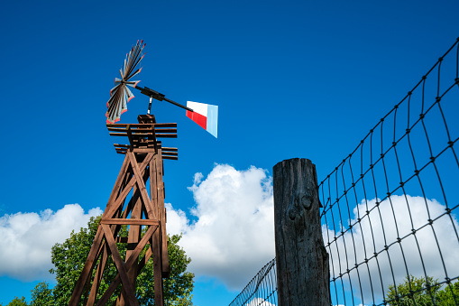 Metal Texas Windmill on Wooden Trestle under Perfect Blue Sky on an open Texas Farm