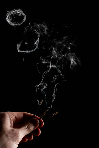 istock Two burning Incense Sticks with smoke on a black backround. incense sticks in a man's hand. 1282688048