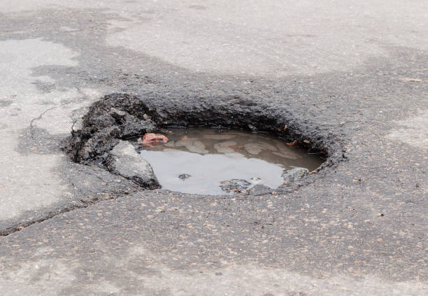 istock Damaged road after winter. Deep pit on the asphalt with puddle. 1282688061