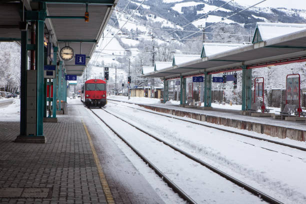 istock Red passenger high-speed train pulls up to stop at deserted snow-covered railway station in mountains. Concept of transport, communication, infrastructure, travel in Europe. Horizontal format 1282688088