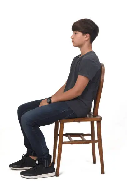 Photo of teenage boy sitting on a chair with white background