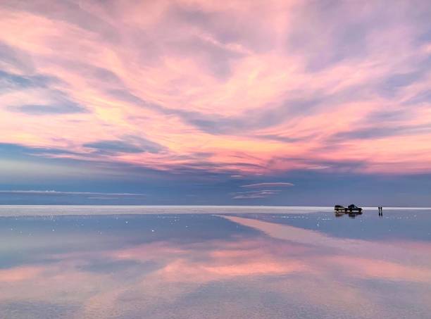 輝く塩湖水の中に魔法の雲の反射とファンタジーピンクの夕日 - ウユニ塩湖 ストックフォトと画像