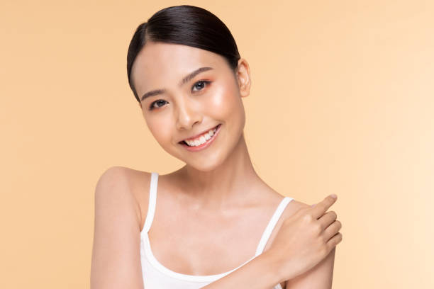 istock Beautiful Young Asian Woman Looking While Touching Shoulder feeling so happy and cheerful with healthy Clean and Fresh skin,isolated on Beige background,Beauty Cosmetology Concept 1282695899