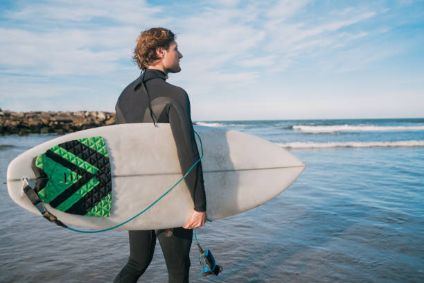 istock Surfer standing in the ocean with his surfboard. 1282696971