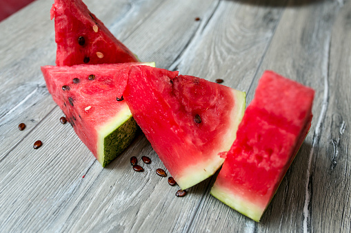 This is an outdoor photograph of a plate of sliced triangle watermelon sitting on a plate of a plate of sliced triangle watermelon sitting on a plate with a glass of watermelon juice and mint