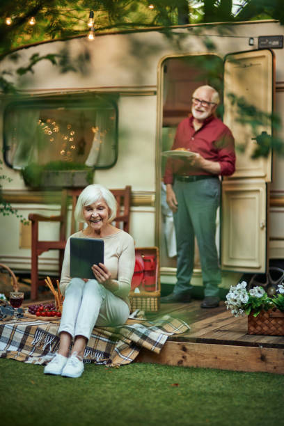istock Happy elderly lady holding gadget while sitting on the van porch 1282700646