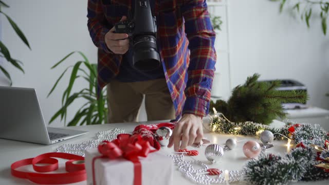 Tilt up and down of professional young photographer taking Christmas flatlay images with camera in office