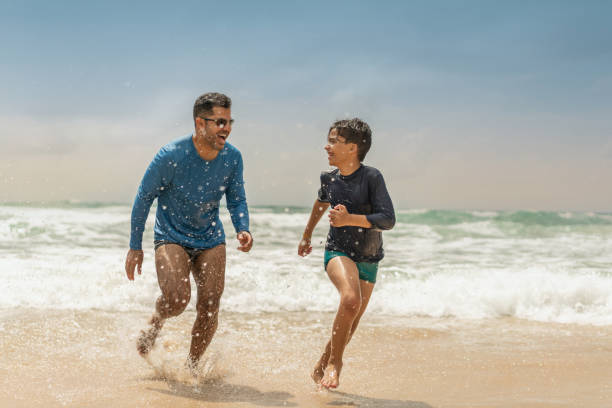 padre e hijo jugando en la playa - child running playing tag fotografías e imágenes de stock