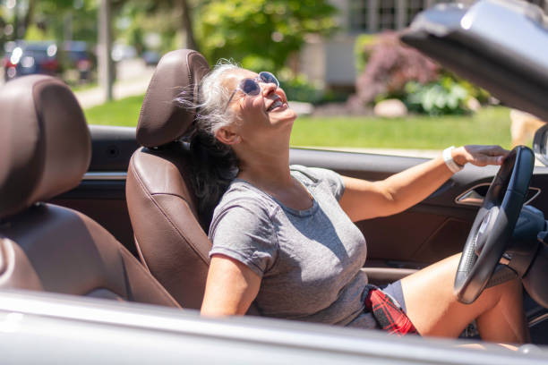 una donna anziana in una decappottabile in una calda giornata estiva - car insurance women driving foto e immagini stock