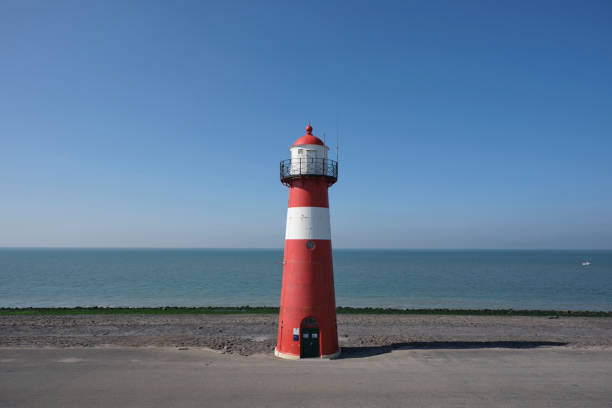 istock Red and white lighthouse on a blue sky background, Westkapelle in The Netherlands 1282711546