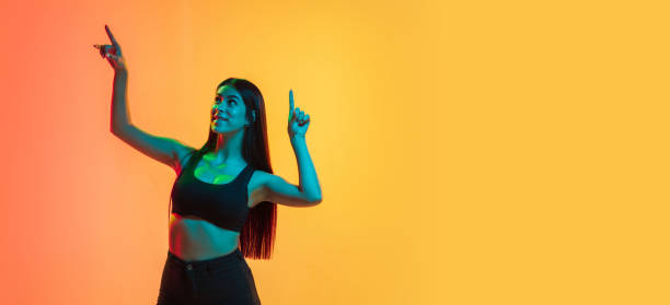 istock Young woman's portrait on yellow-orange studio background in neon light 1282711711