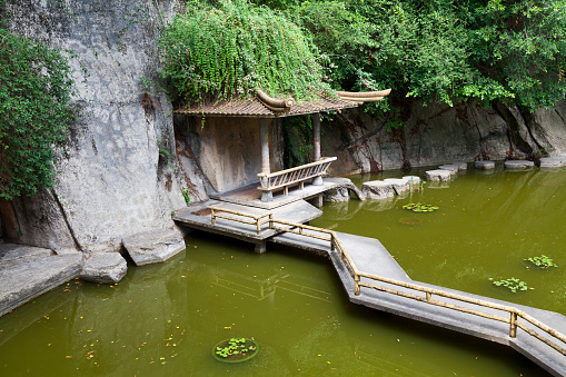 Small footbridge over a pond heading to a pavilion in a public park on Jinbang Hill in Xiamen, China.