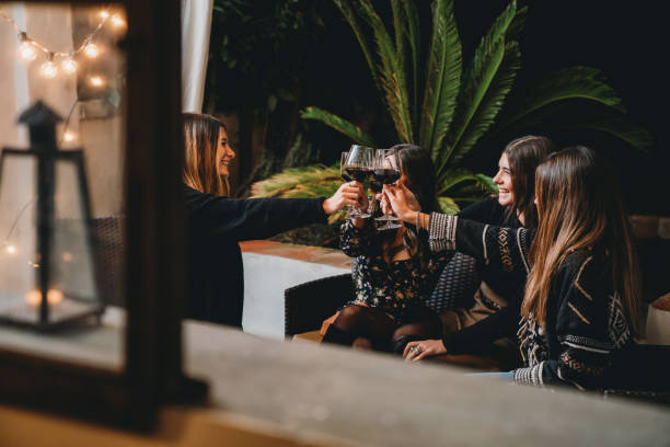 Friends toasting together with red wine during a patio dinner aperitif
