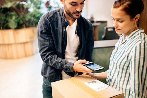 Courier scanning package with smart phone at office reception